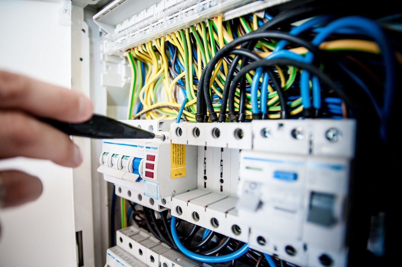 Close-up of an electrical distribution panel with colour-coded wiring and a screwdriver at a breaker terminal