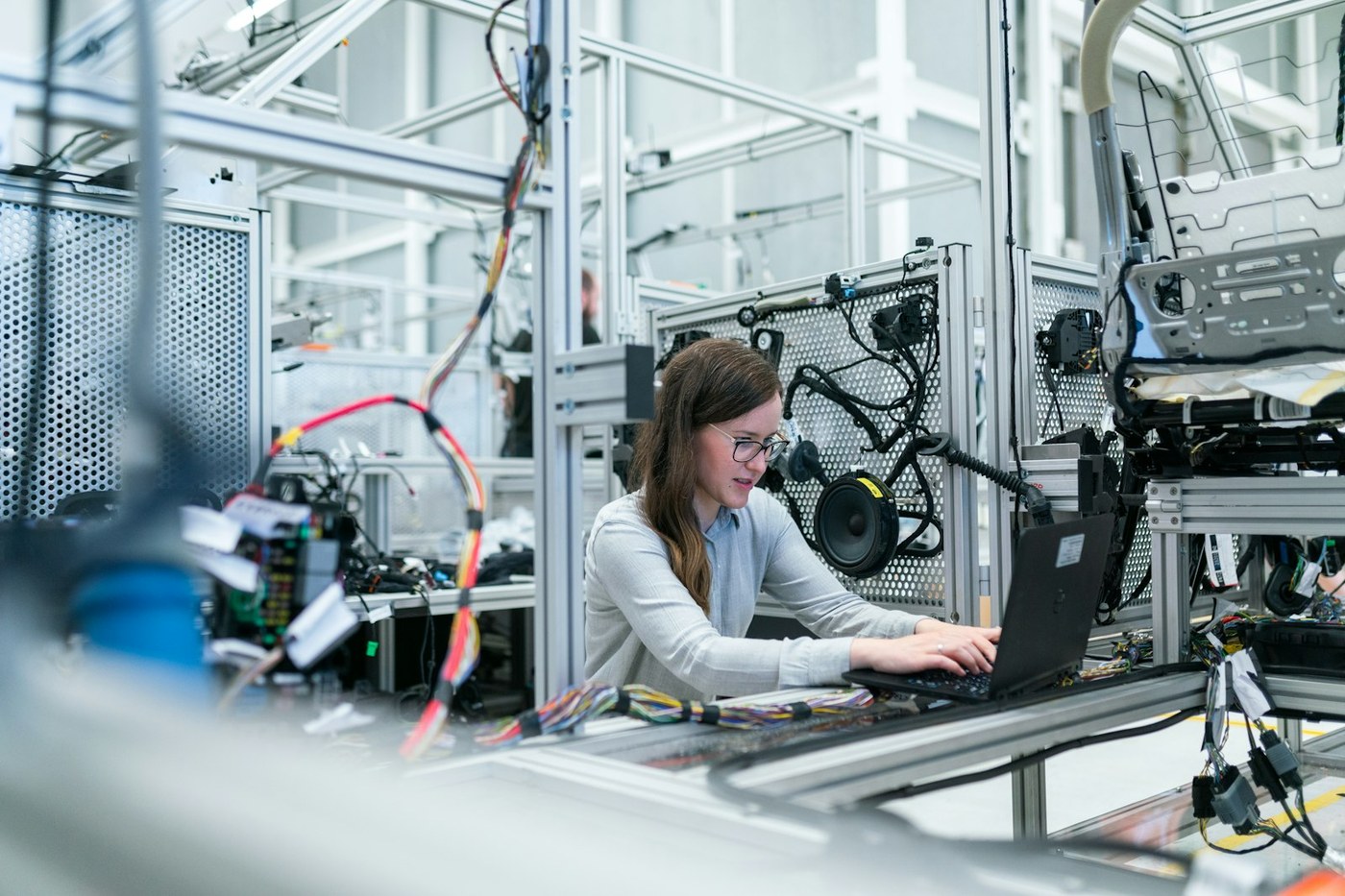 Engineer using a laptop beside industrial wiring and modular aluminium framing in a technical lab