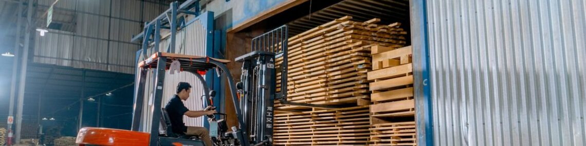 Man driving a forklift loaded with pallets inside a warehouse