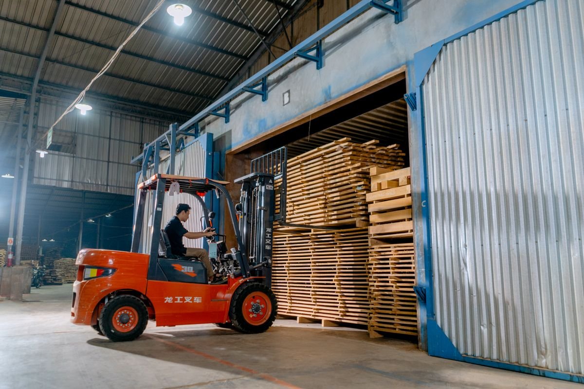 Man driving a forklift loaded with pallets inside a warehouse